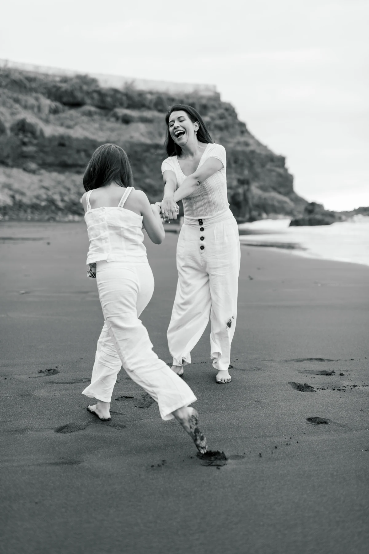 A mother and daughter playing on the beach, in black and white.