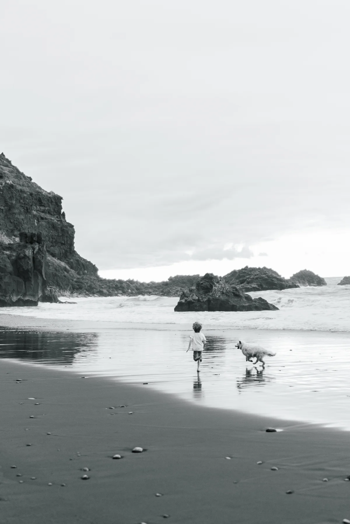 Children and their parents walking by the water, in black and white.