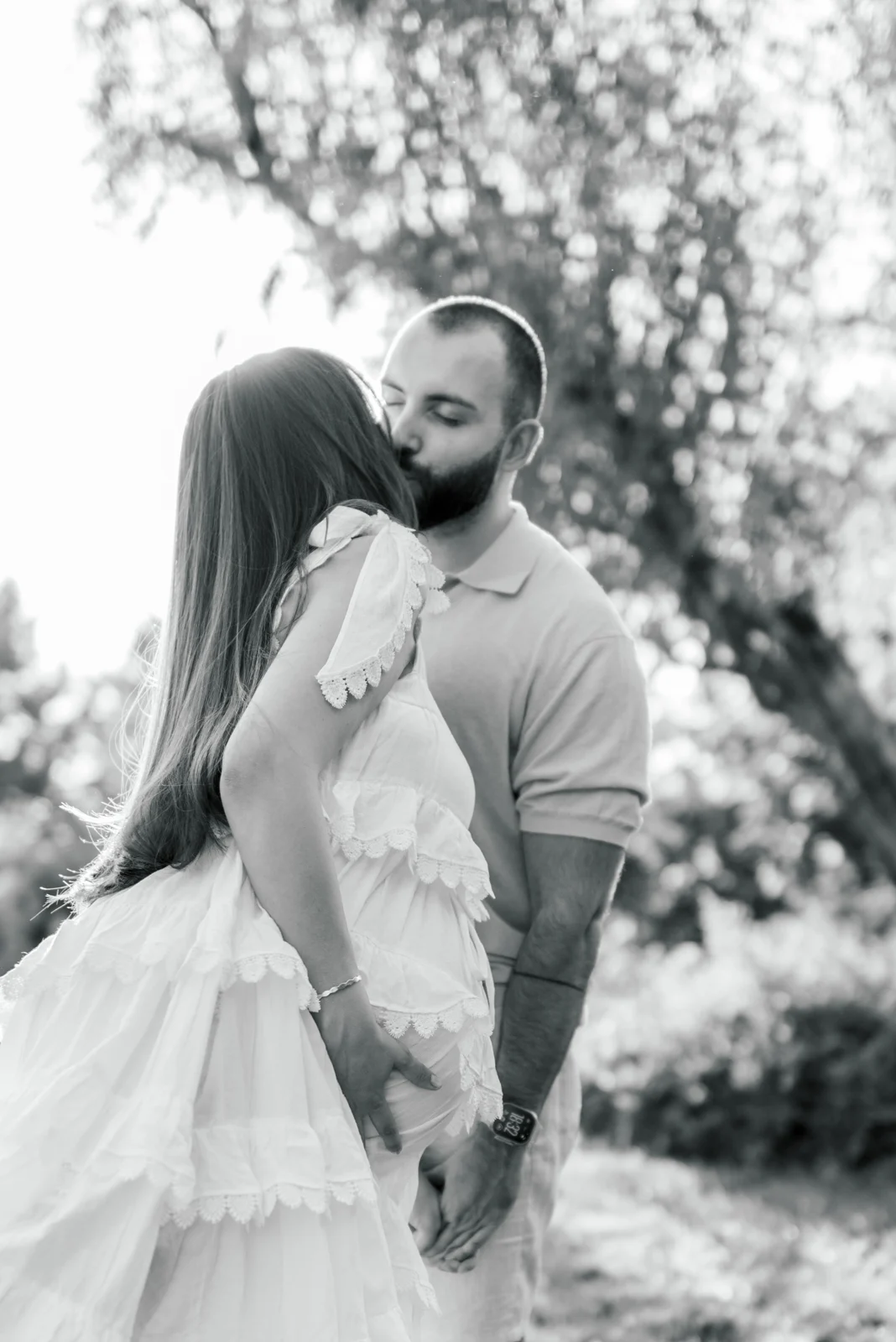 An expectant couple embracing, in black and white.