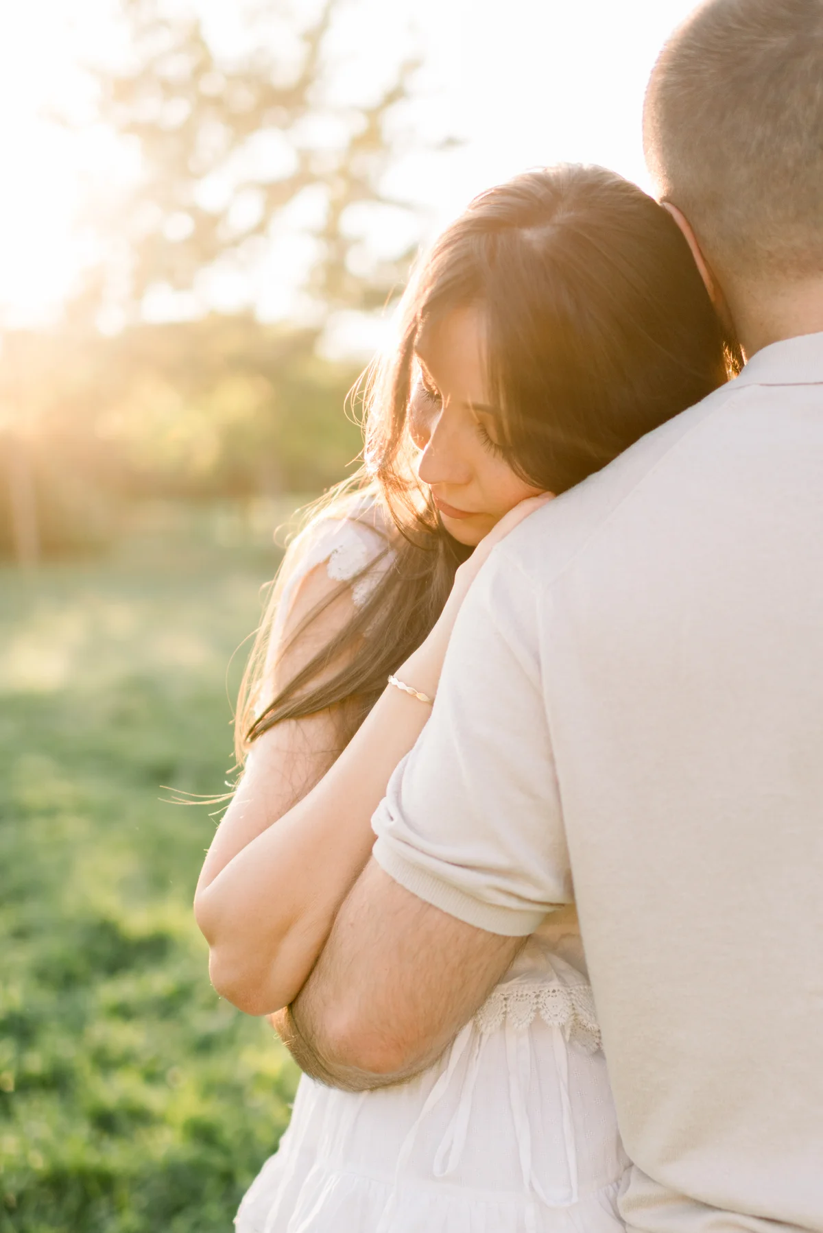 An expectant mother leaning on her partner’s shoulder in the warm evening light.