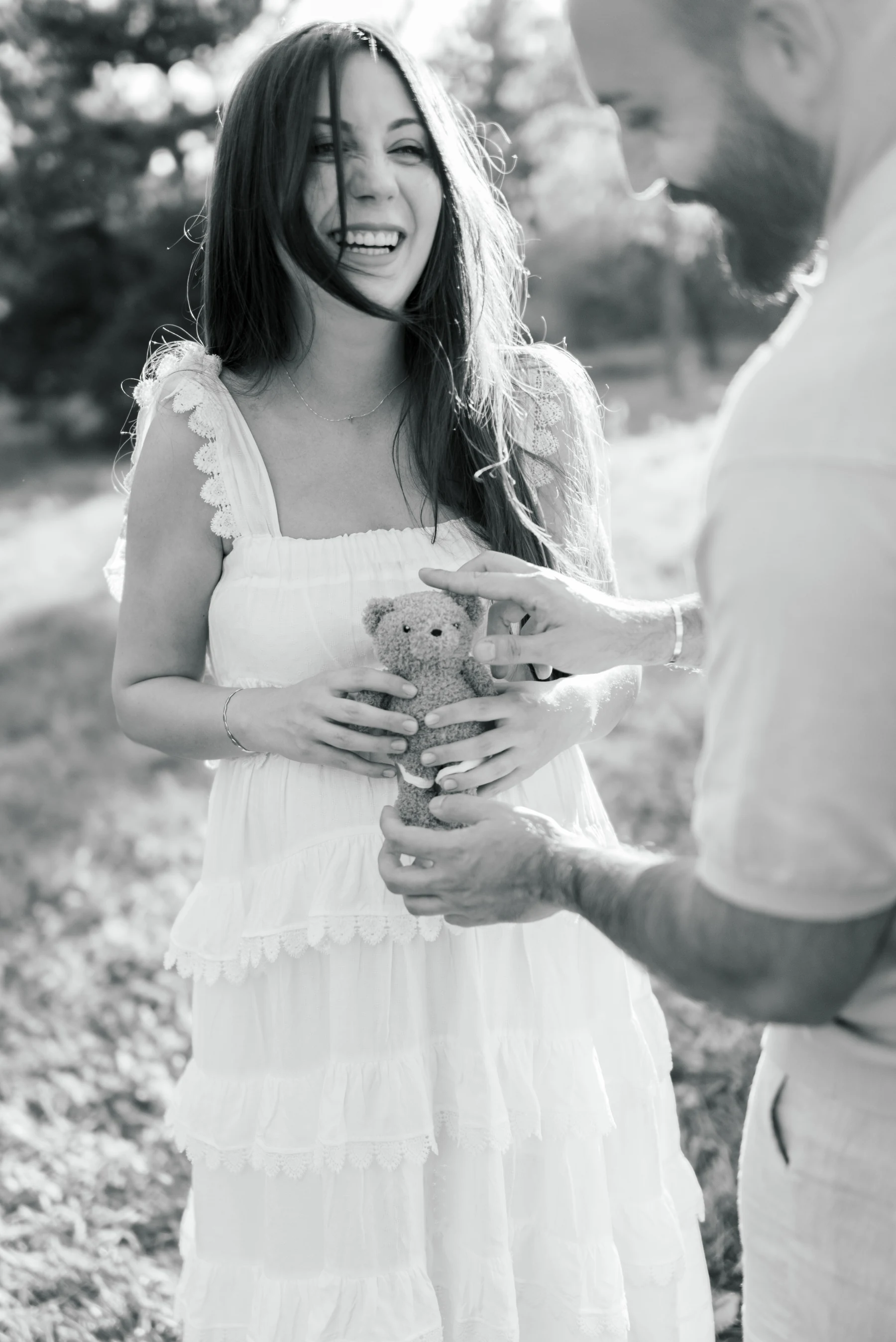 An expectant couple laughing together, in black and white.