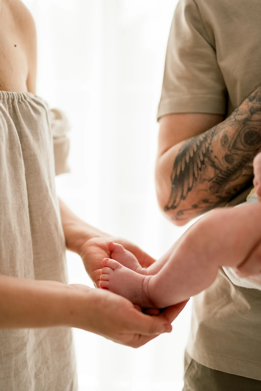 Parents cupping their baby’s tiny feet in their hands together.