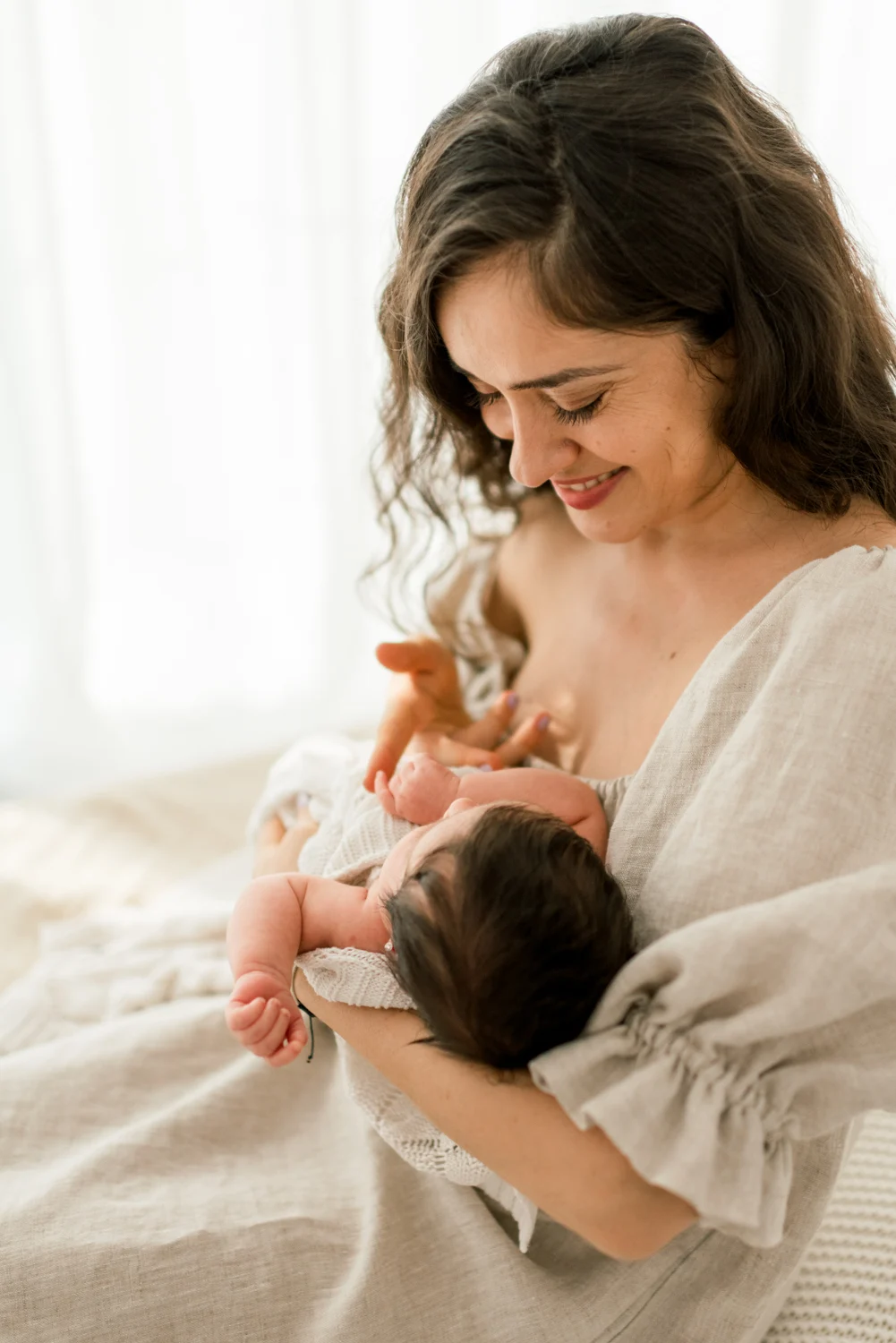 A mother smiling down at her newborn in her arms.